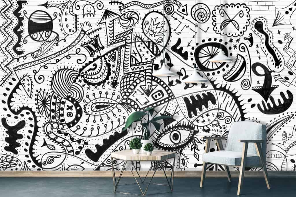 The living room's white wall is a canvas of intricate black doodles and abstract designs, embodying the theme *making your mark*. The wallpaper features detailed line art, geometric shapes, swirling patterns, and unique motifs in stark black against a pristine white background.