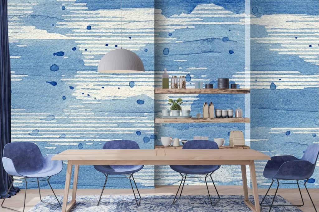 The wallpaper in the modern dining area features an abstract design in shades of blue and white. The design includes fluid, dynamic patterns that may resemble brush strokes or water ripples. Various tones of blue—from deep navy to light sky blue—create a sense of depth and movement. White spaces intersperse the blues, adding contrast and highlighting the abstract forms.