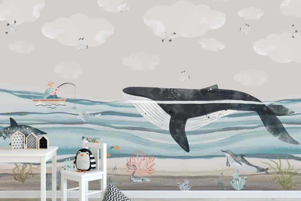 Whimsical mural, underwater scene, large whale, fish, dolphins, small boat with fisherman above water. Pastel colors: blues, pinks, and greens. Penguin toy and house-shaped decor in foreground.