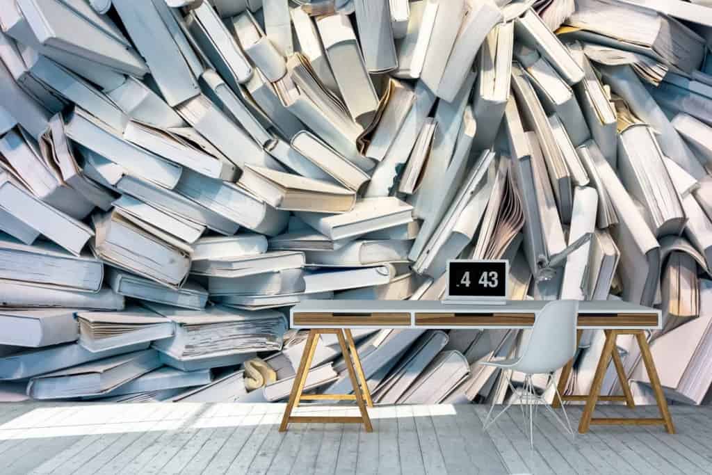 The wallpaper features an artistic depiction of abundant knowledge with white books stacked haphazardly, highlighting a minimalist yet striking design. The primary element is the large array of white books, creating a visually stimulating backdrop with its detailed and organized chaos.