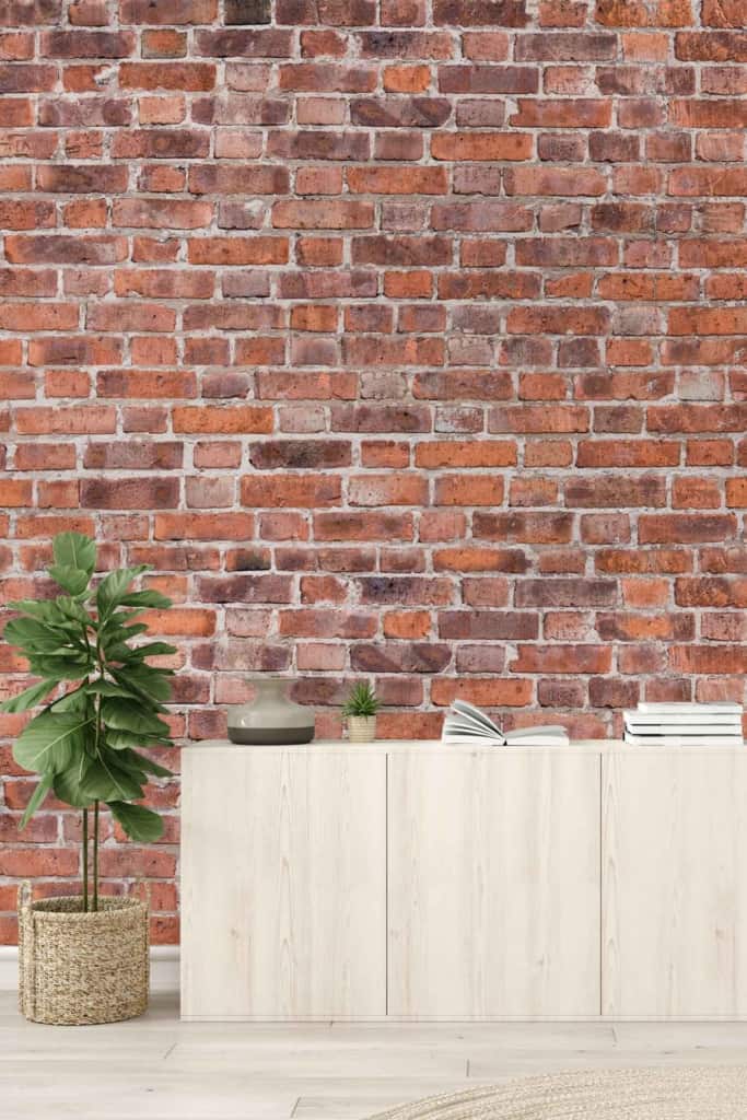 The wallpaper features a rustic design with exposed bricks in various shades of earthy red, brown, and occasional hints of white. The texture mimics the rough and aged look of real brickwork, enhancing the room’s minimalist aesthetic.