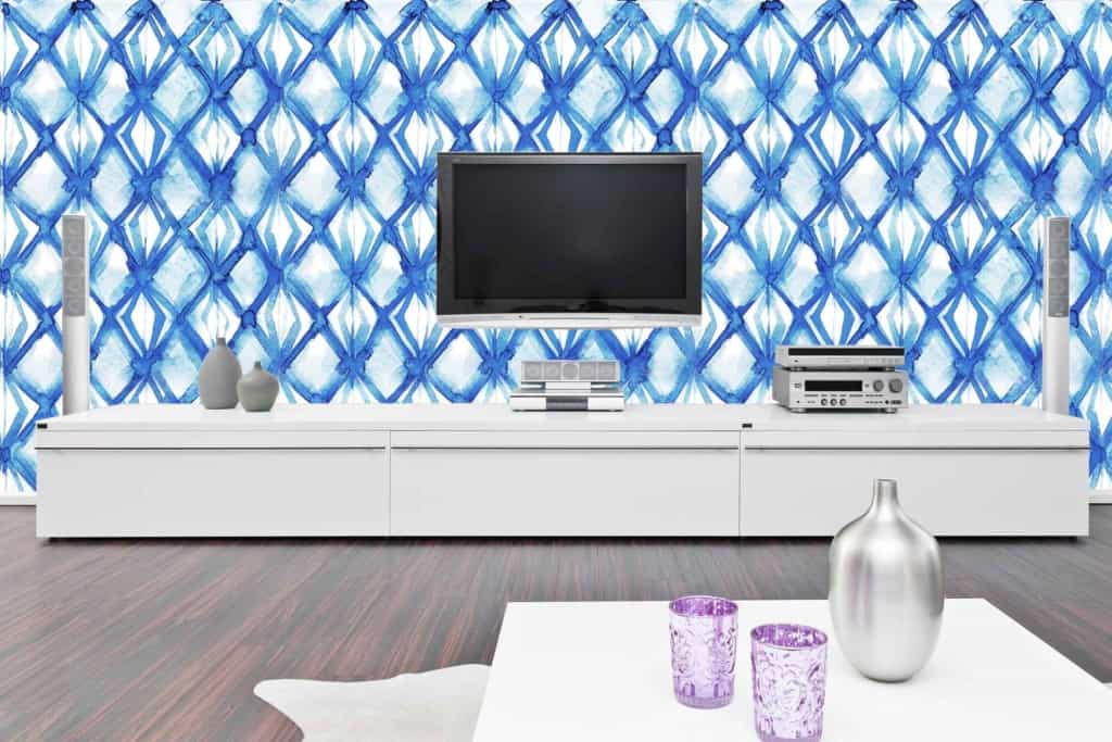 The wall showcases a striking blue geometric pattern with interlocking diamond shapes. This wallpaper consists of varied shades of blue, ranging from deep navy to lighter azure, creating an eye-catching and dynamic look.