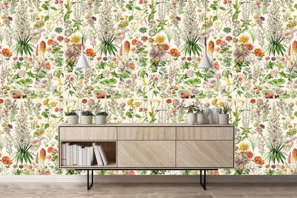 The wallpaper features vibrant floral patterns with blooming roses, daisies, and peonies in shades of pink, red, yellow, and white. Lush green leaves intertwine throughout the design. The pattern is rich with botanical elements from Elizabeth's Garden collection.
