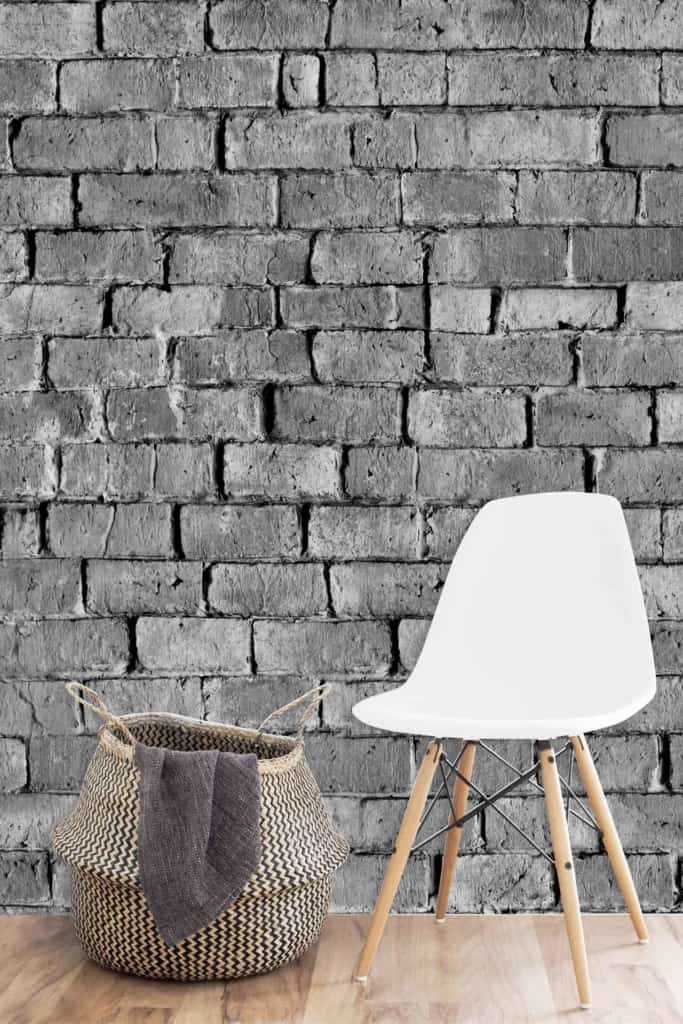 A textured gray brick wallpaper featuring various shades of gray provides a sophisticated and subtle backdrop. The wall displays irregularly shaped bricks that create a modern, minimalist aesthetic with natural textures and refined color variations.