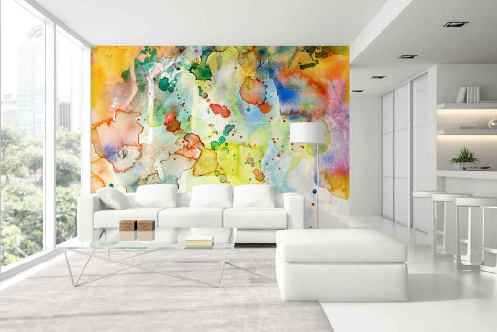 The focal point of the modern living room is a striking abstract watercolor mural crafted with Jacksons' premium paint. The wallpaper features dynamic swirls of deep blues, vibrant yellows, and calming greens, seamlessly blending with hints of soft purples and subtle pinks. Bold splashes and delicate brushstrokes create a sense of movement and depth. The large-scale design ensures that each element—from intricate dots to broad strokes—contributes to a visually captivating centerpiece.