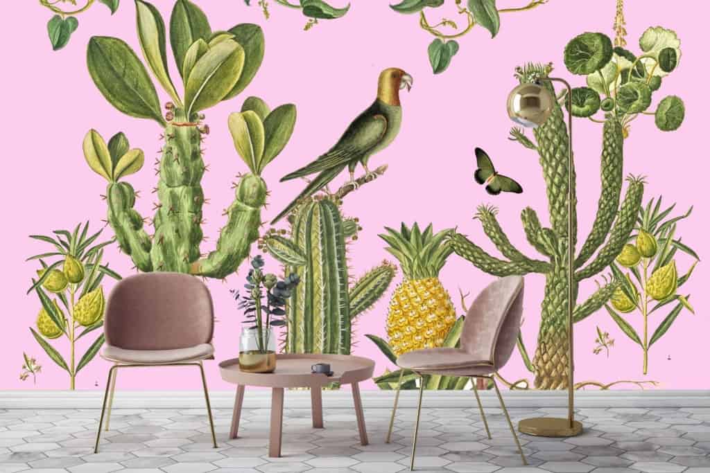 Pink wall with a vibrant tropical-themed mural. Elements include cacti, pineapples, and a colorful parrot. Bright green tones for the cacti, yellow for pineapples, and multi-colored feathers on the parrot. A butterfly in motion near the mural adds dynamic interest.