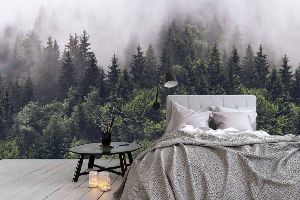 The wallpaper in the modern bedroom features a large mural of dense, misty pine trees. The colors include various shades of green and gray, creating a serene and calming atmosphere with the foggy forest theme.