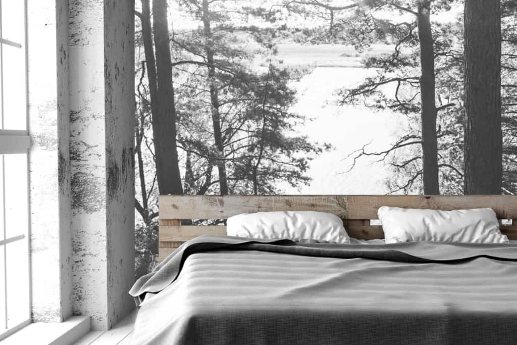The wallpaper in the bedroom features a black-and-white mural of a forest and lake. Intricate trees, serene water, and natural elements dominate the scene, providing an elegant yet tranquil backdrop.