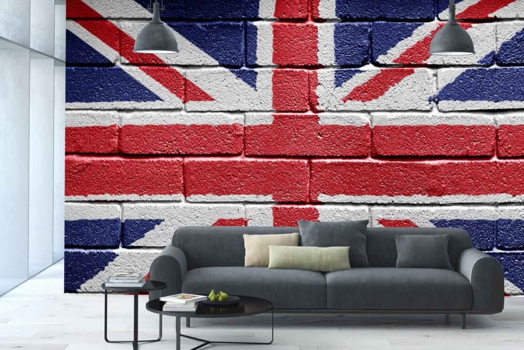 The wallpaper features the iconic Union Jack design, showcasing bold and vibrant colors of deep blue, bright red, and stark white. The pattern consists of intersecting crosses and diagonal lines combining elements from the flags of England, Scotland, and Ireland. This striking mural adds a patriotic touch with a classic yet modern vibe to the living room.