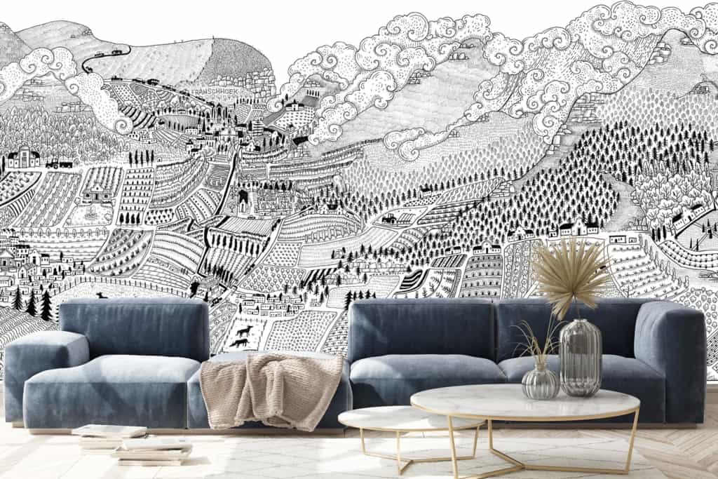 A detailed monochromatic mural of the Cape Winelands' hilly landscape features mountains, forests, fields, and villages. The intricate artwork combines whimsical elements with textured details in shades of black, white, and gray.