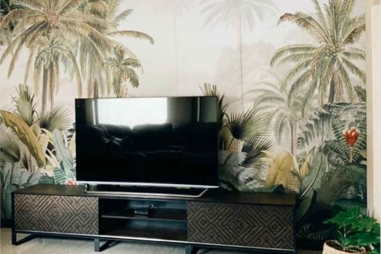 Tropical-themed wall mural features lush green palm trees and dense foliage. Elements include vivid green leaves, various shades of tropical greenery, and intricate leaf patterns. The backdrop creates an exotic jungle ambiance with its rich array of verdant hues and natural textures. Perfect for adding a vibrant, nature-inspired touch to any space.