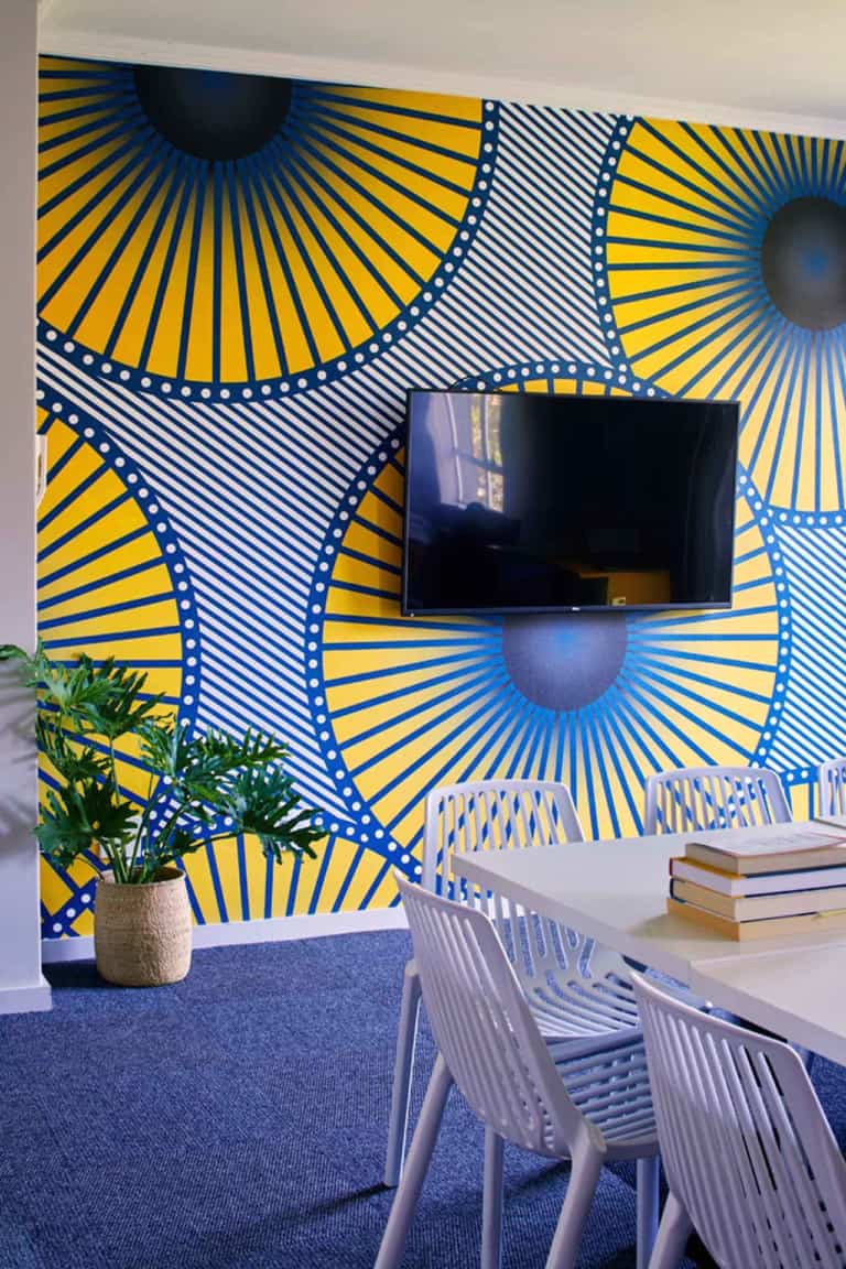 Modern room wallpaper: vibrant yellow and blue, large circular designs, bold patterns.