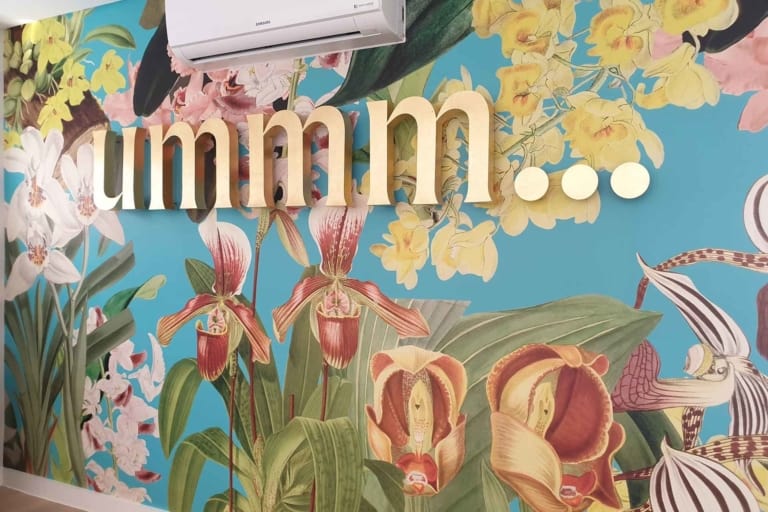 A vibrant wall mural of colorful orchids in shades of pink, purple, yellow, and white amid lush green foliage.