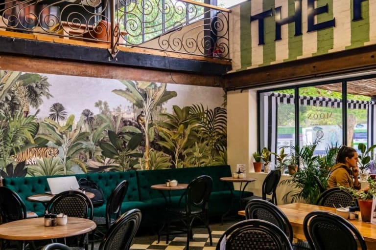 The wallpaper is lush and jungle-themed, featuring vibrant green foliage, tropical plants, and exotic flowers. It includes various shades of green, splashes of vibrant colors like deep reds, oranges, and yellows. Detailed leaves and botanical patterns dominate the design.
