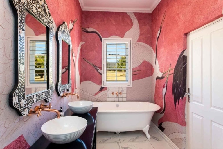 A bathroom with **pink and red wallpaper** featuring **large crane designs**.