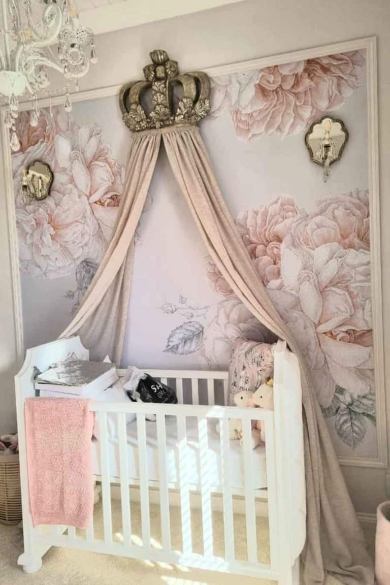 The wallpaper features large pastel floral prints in shades of soft pink, lavender, and mint green. Delicate petals and lush leaves create an elegant, serene backdrop perfect for a cozy nursery setting.