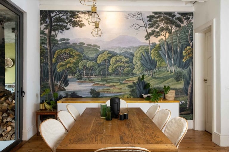 The wallpaper features a lush, green forest with a pond. Elements include towering trees, dense foliage, and serene water. Colors found are various shades of green, from deep emerald to light lime, along with touches of earthy browns and tranquil blues reflecting in the pond's surface.
