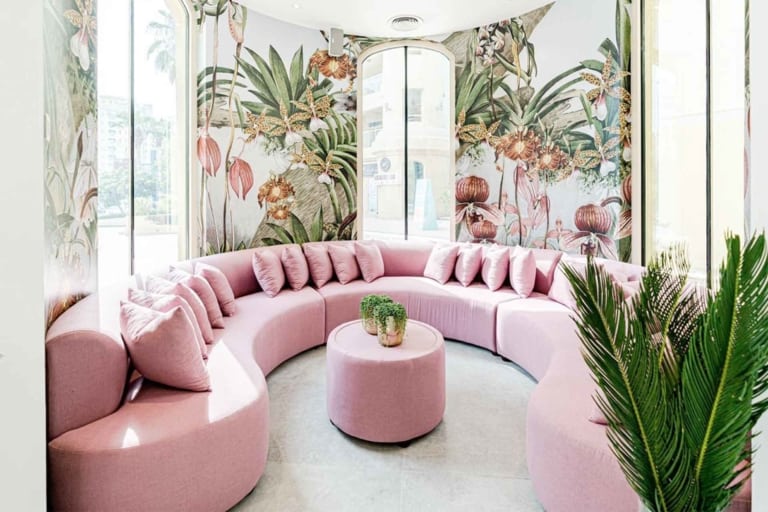 The walls feature vibrant floral and botanical wallpaper. Elements include a lush array of flowers and plants in a spectrum of colors: deep greens, rich reds, bright yellows, vivid oranges, pastel pinks, and bold blues. This wallpaper provides a colorful backdrop ideal for highlighting personal projects.