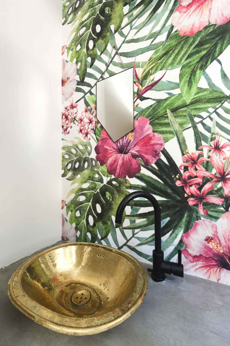 A vibrant tropical-themed wallpaper in the bathroom features lush green leaves and large pink flowers. This eye-catching design is perfect for adding a burst of color and nature-inspired elements to any space.