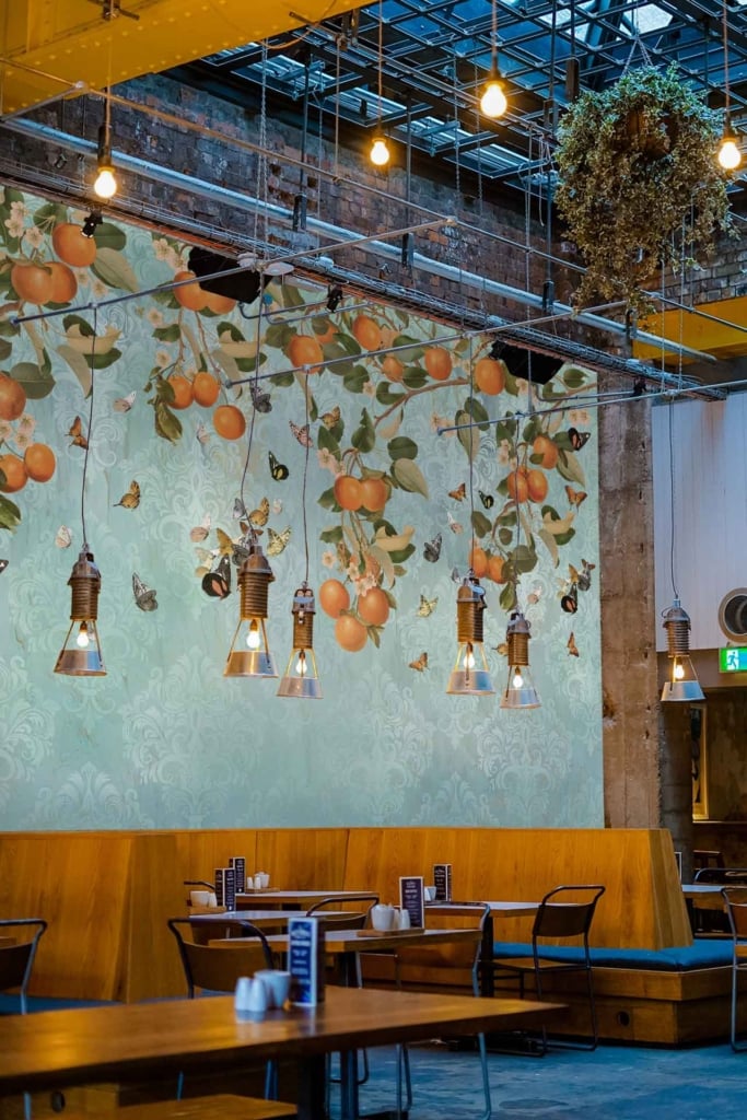 Mural features vibrant oranges and lush green leaves. The design includes rich yellows, deep greens, and earthy tones, creating a fresh, natural aesthetic.