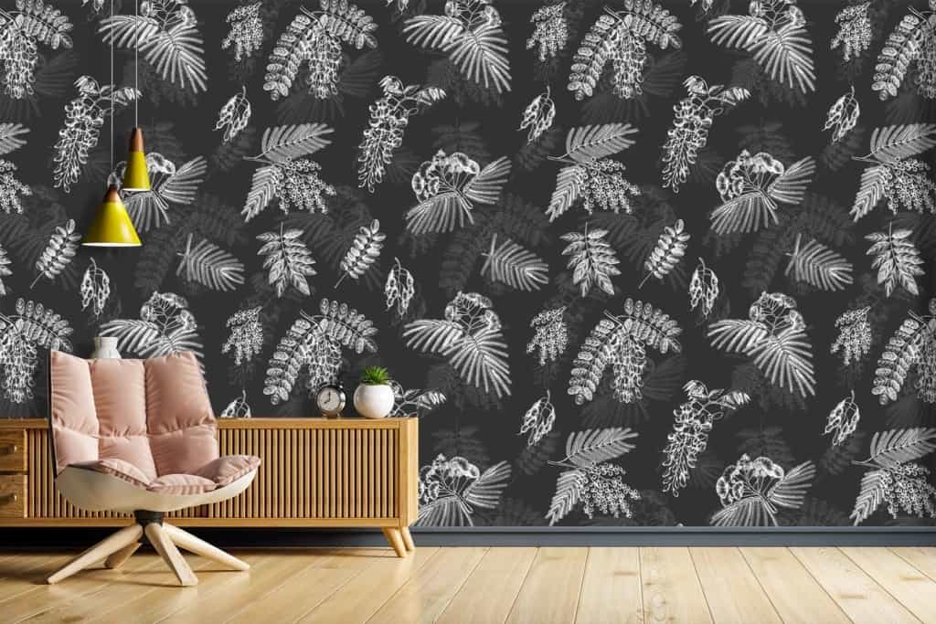 The wallpaper in the modern living room is black and white with botanical patterns featuring leaves and floral designs. The monochrome scheme provides a striking contrast, emphasizing intricate details of vines and blooms.