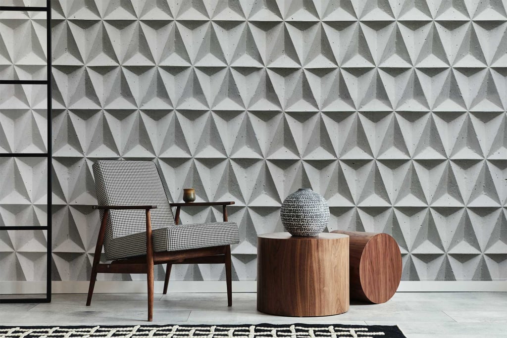 A modern, minimalist living space featuring a patterned geometric wallpaper in muted tones of gray, beige, and white. The wallpaper's design showcases interlocking shapes that add depth and texture to the room.