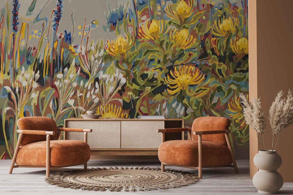 The wallpaper features a vibrant floral mural with large yellow Chinkerinchee flowers, green leaves, and splashes of pink and blue accents. The design is bold, colorful, botanical, and showcases oversized flower motifs.