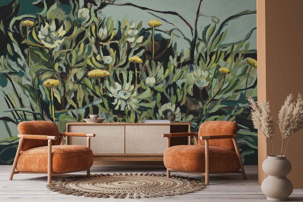 Wallpaper features a vibrant mural of green plants, yellow flowers, and distinctive Protea scolymocephala blooms from the 2024 growth series. The pattern includes lush botanical elements in various shades of green, bright pops of yellow floral detail, and textured protea flowers with intricate shapes. The overall color palette is green and yellow with touches of natural cream and brown accents to mimic real foliage.