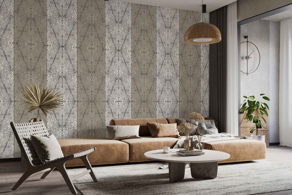 The wallpaper features a modern geometric pattern with soft tan, ivory, and muted taupe tones. Subtle tortoise shell accents are woven into the design, creating a sophisticated and textured look. The pattern combines organic shapes with linear elements, complementing neutral decor while adding visual depth to the living room.