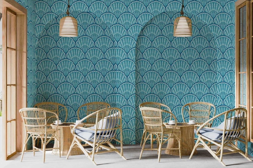 Blue scallop-patterned wallpaper with Memphis-inspired design; features rounded, repetitive wave-like shapes in various shades of blue, accented by graphic motifs and playful geometric elements in contrasting colors such as white, pastel pinks, and yellows.