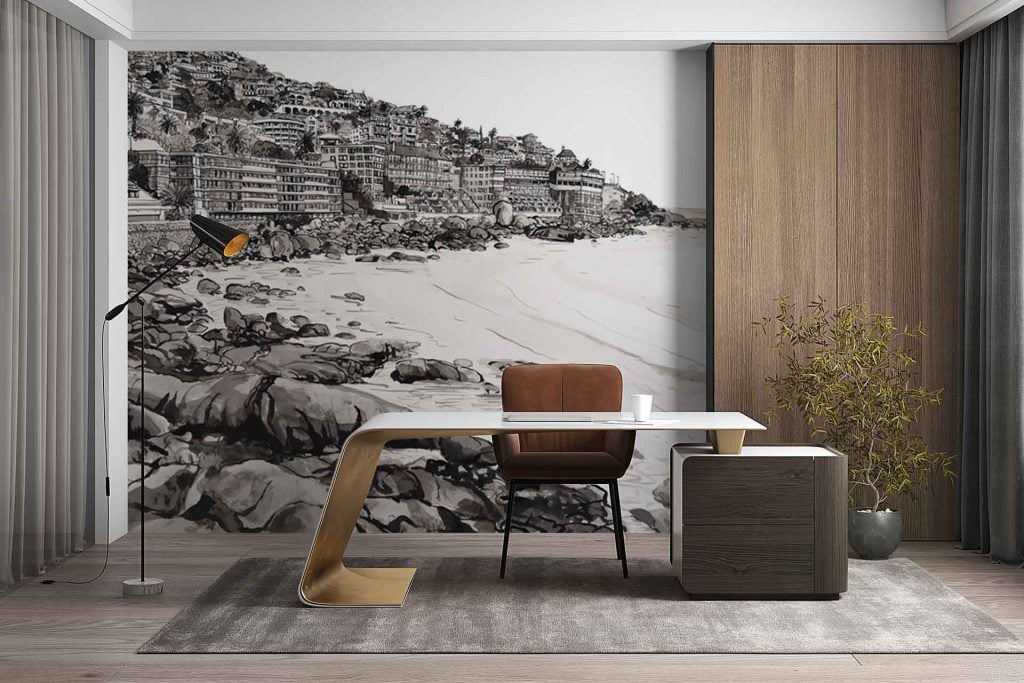 The wallpaper features a large mural of Thibault Square’s coastal town, depicting buildings perched on dramatic cliffs above a rugged, rocky shoreline. Architectural details of the town are visible—rooftop shapes, windows, balconies—set against natural elements like stone cliffs and the sea. The color palette centers around neutral tones: soft grays, warm beige, muted browns, creamy whites, and subtle hints of blue from the water. The scene blends urban structure with nature in serene harmony.