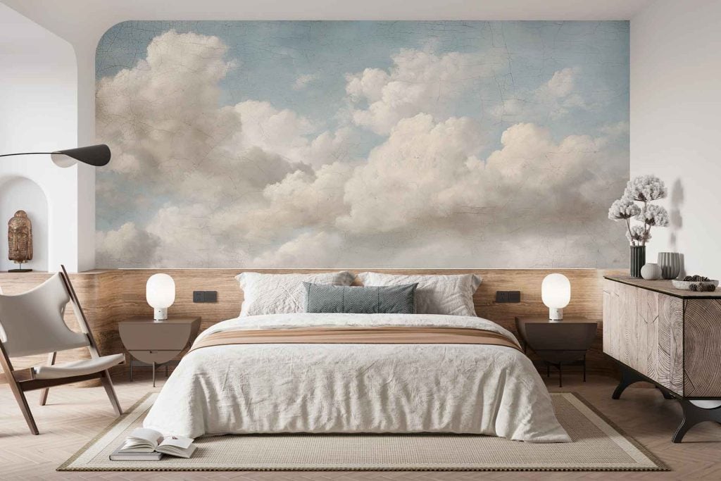 The wallpaper features a modern cloud mural in soft, neutral tones—primarily beige, white, and warm greys. The design showcases gentle, painterly clouds with subtle gradients and blurred edges for a calming, dreamy effect. Hints of cream and taupe add depth without overpowering the minimalist aesthetic.