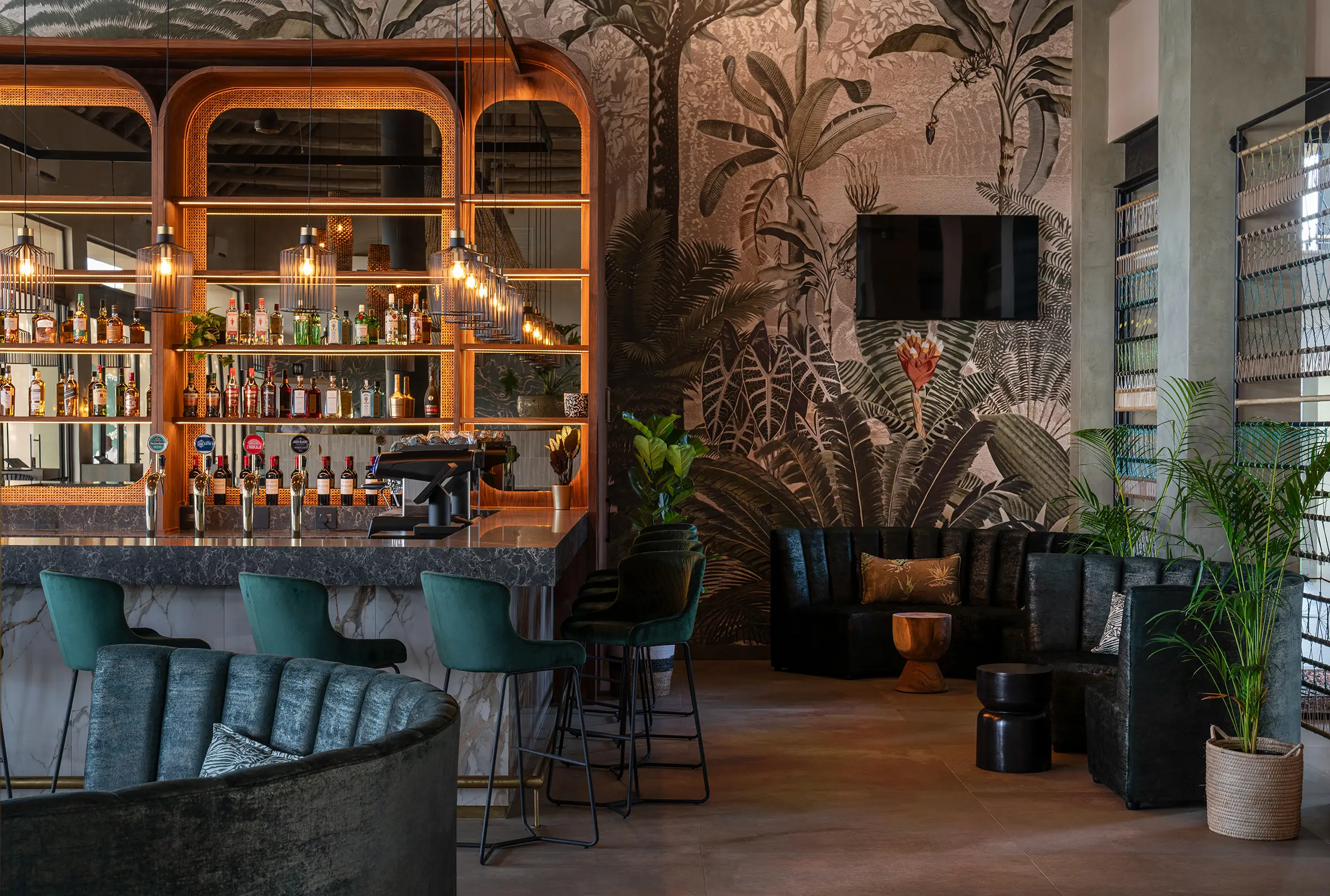 Large tropical-themed wall mural featuring lush green palm leaves, vibrant exotic flowers in shades of pink and orange, and detailed botanical patterns; the wallpaper brings a lively jungle atmosphere with rich greens and colorful accents.