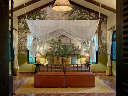 The bedroom features a vibrant tropical mural wallpaper on the back wall, showcasing lush green palm leaves, tropical flowers in pink and orange hues, and hints of blue sky, adding a bold and colorful botanical accent to the room's decor.