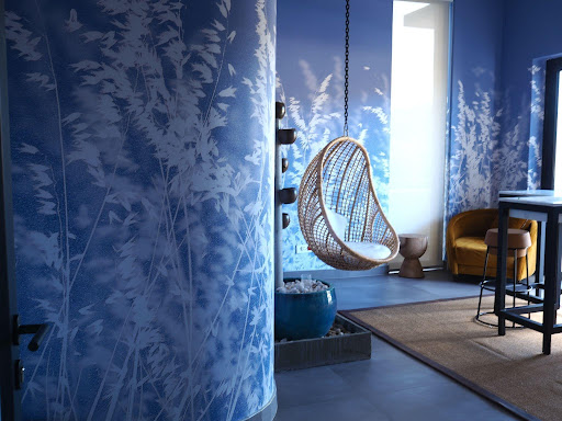 Blue walls adorned with white botanical wallpaper featuring leafy plant patterns. The design contrasts crisp white leaves and stems against a rich blue background, making the botanical motif a focal point of the decor.