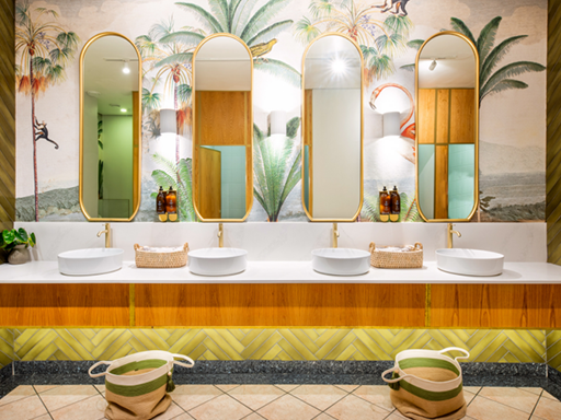 The bathroom's wallpaper is a bold tropical mural featuring lush green palm trees with varying shades of foliage against a light background, adding exotic flair and natural elements to the space.