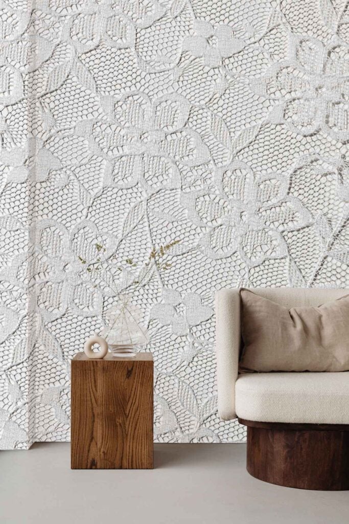 Textured white wallpaper with large, intricate floral designs and lace patterns; decorative elements feature bold flower motifs in soft, neutral tones for an elegant backdrop.