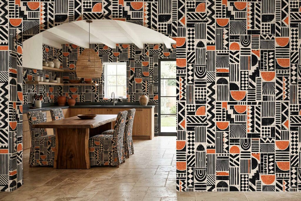 Bold black, white, and orange geometric wallpaper with striking meander motifs covers the dining room and kitchen. The repeating pattern features sharp lines and vibrant colors, making the wallpaper a standout visual element in the space.