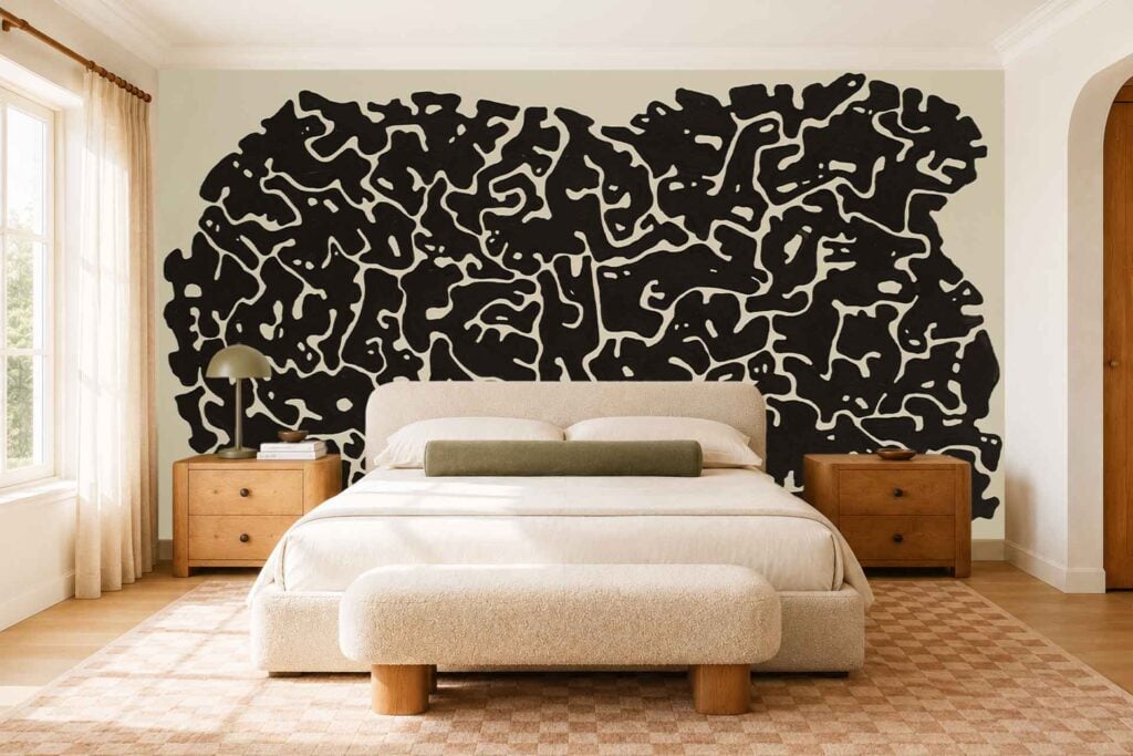 A large, abstract black and white wall mural with bold shapes and graphic contrasts serves as the bedroom’s backdrop. The wallpaper features sweeping forms in varying shades of black, gray, and white.