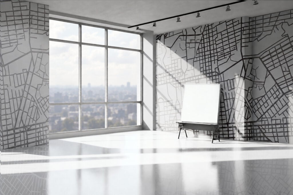 Abstract map designs decorate the walls, featuring intricate lines and shapes in varying shades of gray and white. The wallpaper’s modern patterns add a geometric, urban feel to the office space.