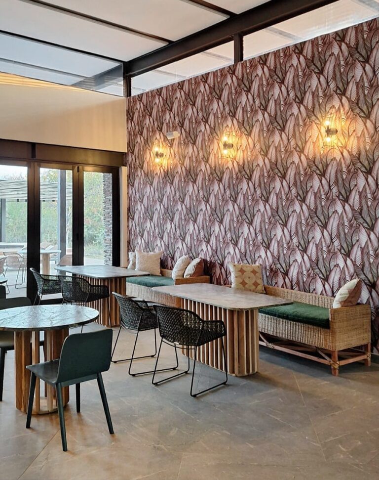 Feature wall adorned with leaf-pattern wallpaper showcasing various green hues and botanical shapes, creating a lush, nature-inspired backdrop.